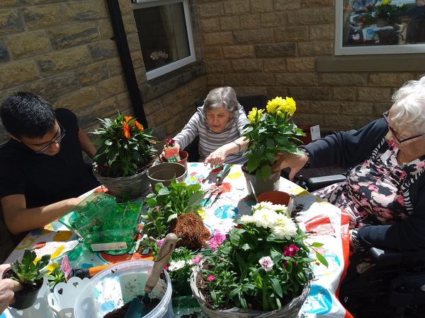 Our residents sat around a table planting flowers in pots at The Porterbrook Care Home