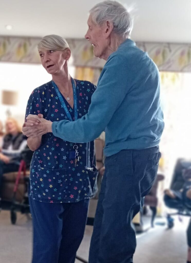 two residents dancing together in the lounge
