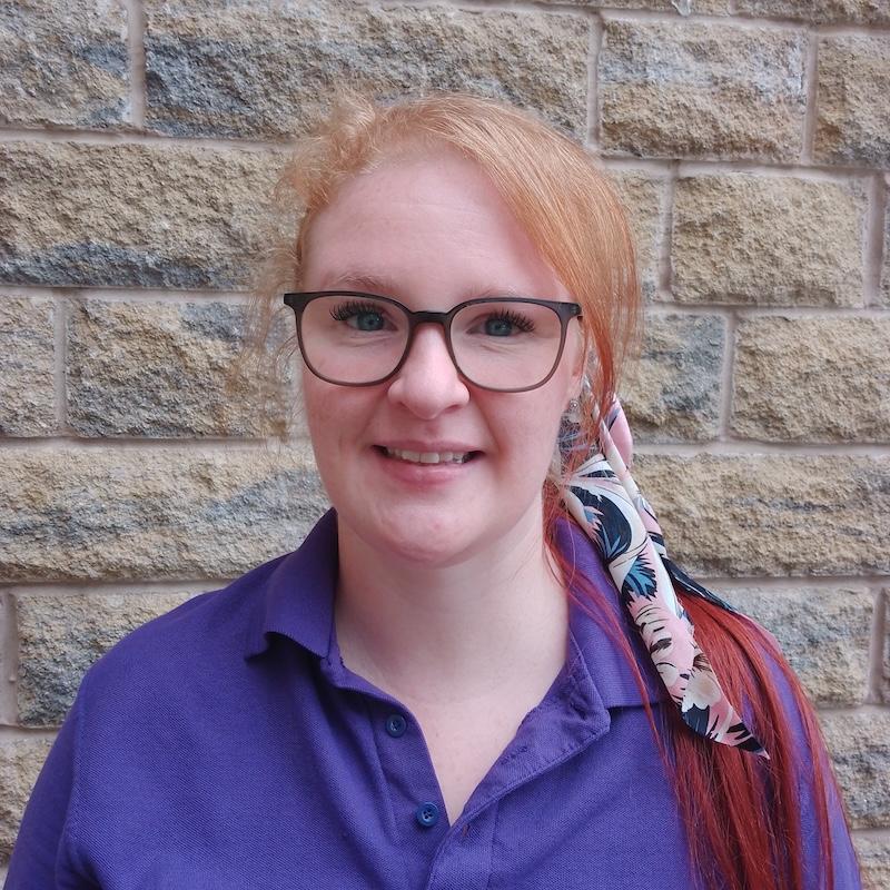 karina one of our activities coordinators stood outsdie in front of a brick wall wearing a purple top