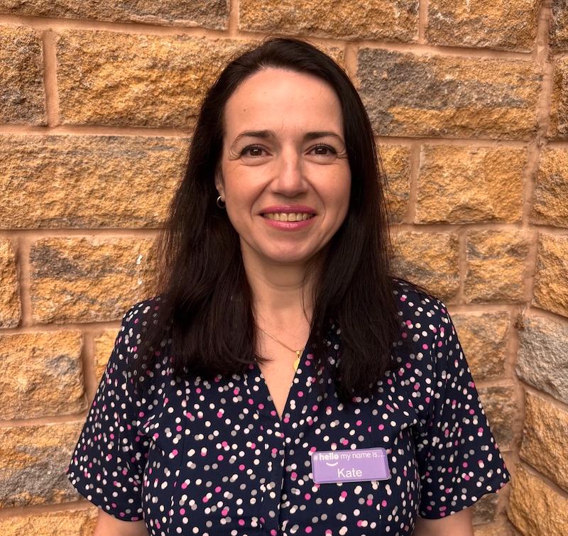 kate our administrator stood outside in front of a brick wall wearing a black and white blouse