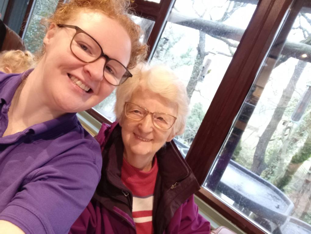 lady with glasses in a purple shirt smiling with an older lady