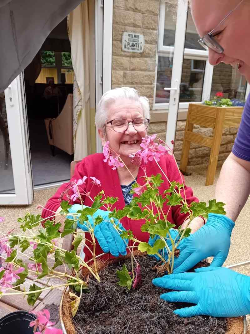 female resident sat down smiling while gardening